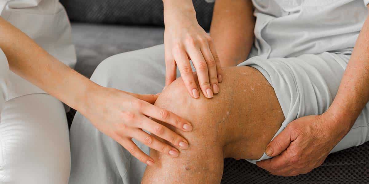 Mão de fisioterapeuta pegando no joelho de paciente - site Dr. Marcelo Correa - Reumatologista em Belém - PA