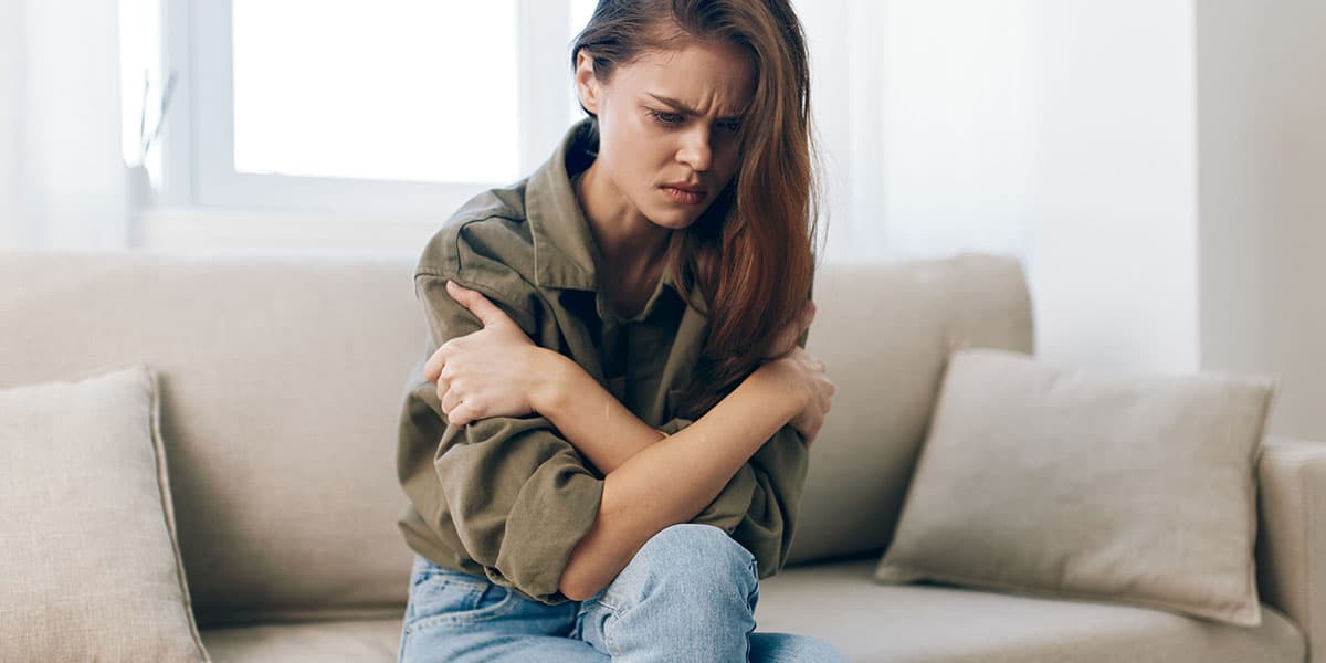 Mulher sentada no sofá pensando se fibromialgia pode matar - site Dr. Marcelo Correa - Reumatologista em Belém - PA